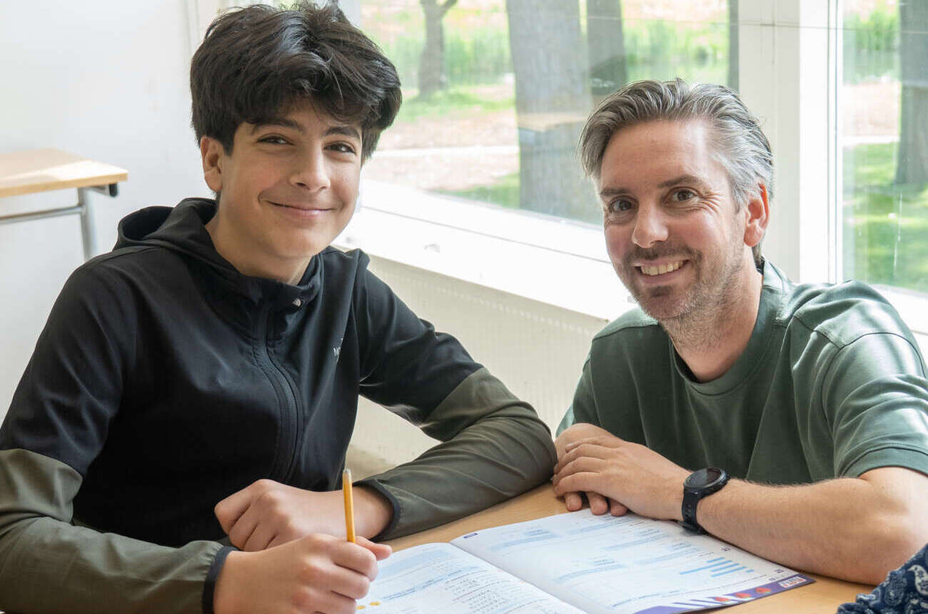 Leerkracht begeleidt een leerling 1-op-1 bij het schoolwerk in een klaslokaal van De Regenboog