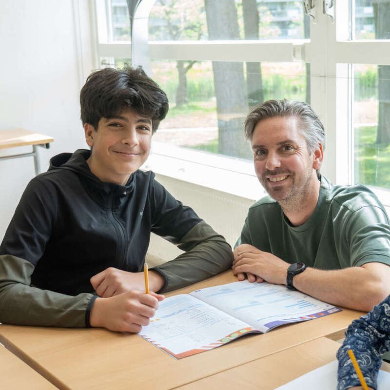 Leerkracht begeleidt een leerling 1-op-1 bij het schoolwerk in een klaslokaal van De Regenboog